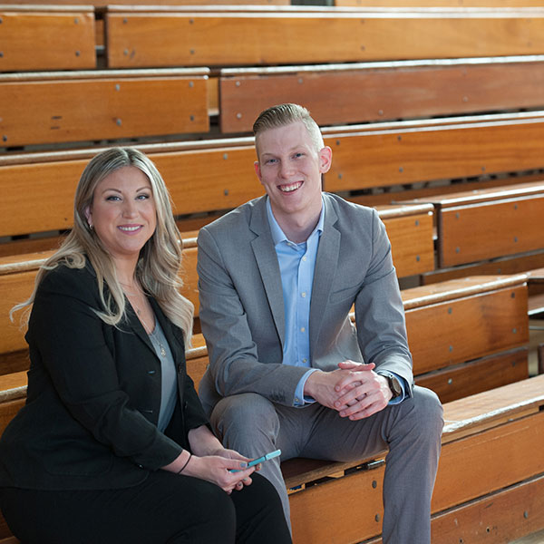 Phaedra and Ben sit on school bleachers, prepping for a client event Phaedra and Ben sit on school bleachers, prepping for a client event